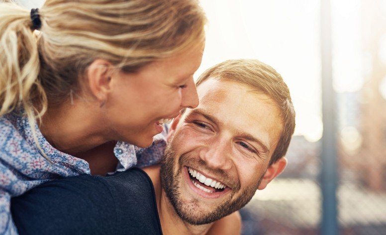 Man and woman sharing bright smiles after teeth whitening