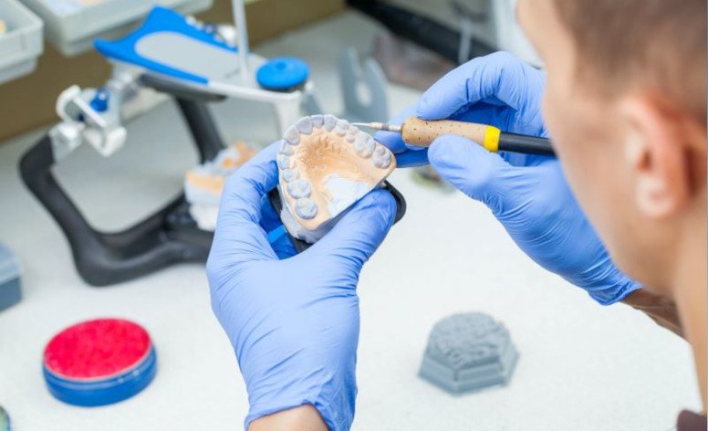 Dental lab technician working with a wax jaw model