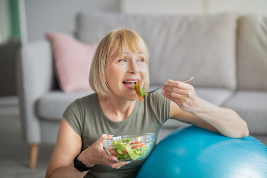 woman smiling while eating salad with dentures