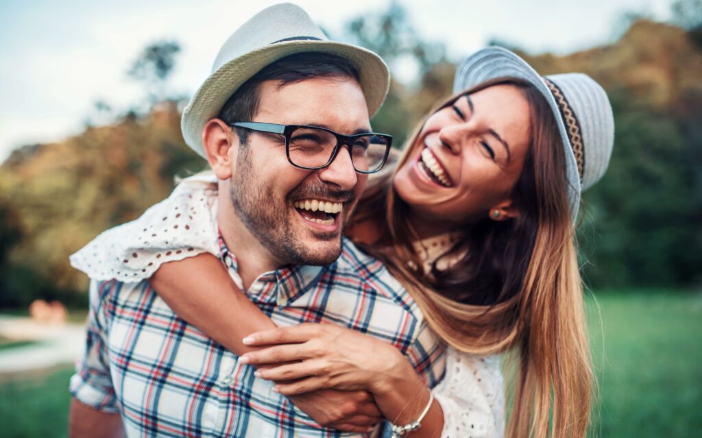 Woman and man in hats outside hugging and laughing